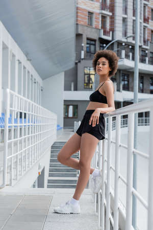 African american sportswoman standing near railing on stadium at daytimeの写真素材