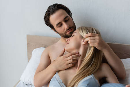 unshaven man hugging blonde woman in bra on bed