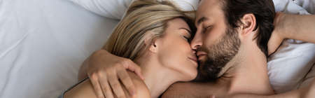 top view of couple in love kissing with closed eyes on bed, bannerの写真素材