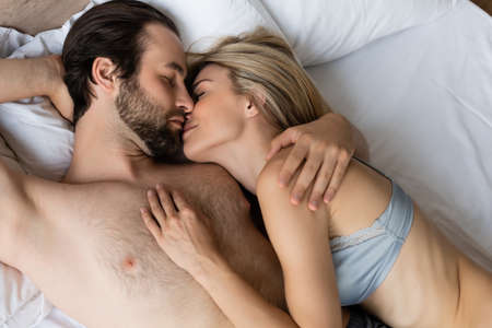 top view of sexy couple hugging and kissing with closed eyes on bed