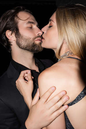 Passionate man kissing blonde girlfriend isolated on blackの写真素材