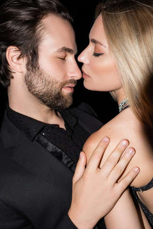 Bearded man in jacket touching blonde girlfriend isolated on black