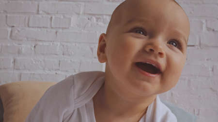 close up of adorable baby laughing near white brick wall