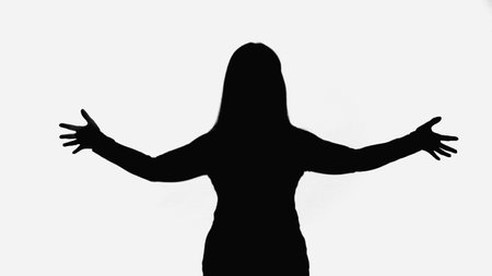 black silhouette of woman standing with open arms isolated on whiteの写真素材