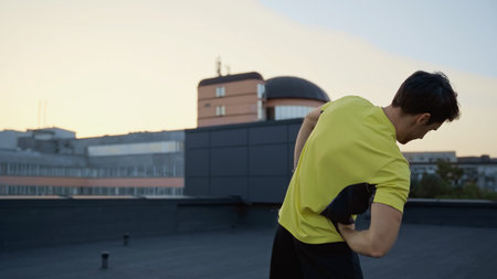 Young brunette sportsman working out on roof in evening