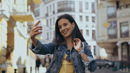 Smiling woman having video call on smartphone on urban streetの写真素材