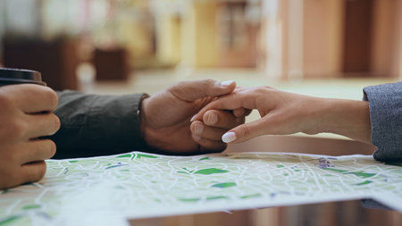 Cropped view of interracial couple holding hands near map outdoors
