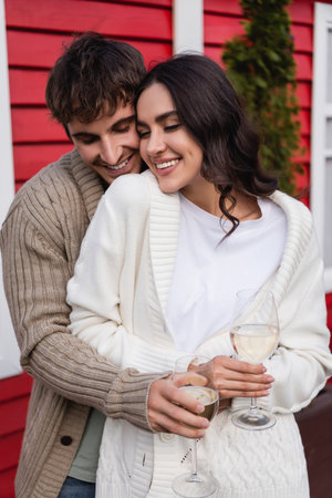Smiling couple in cardigans holding glasses of wine outdoorsの写真素材