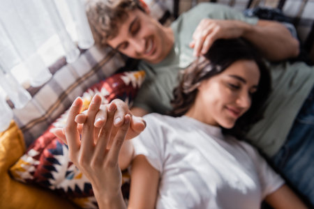 Top view of blurred young couple touching hands on bed in camper vanの写真素材