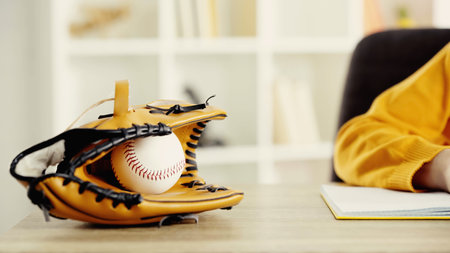 baseball glove with ball near schoolkid doing homework at desk