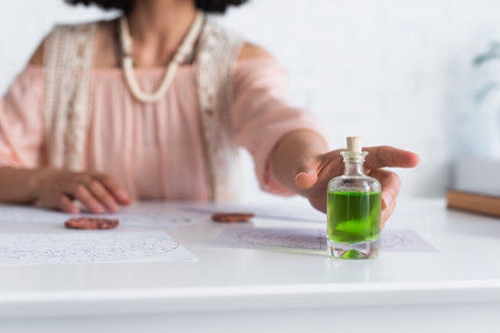 selective focus of bottle with essential oil near cropped astrologer and clay runesの写真素材