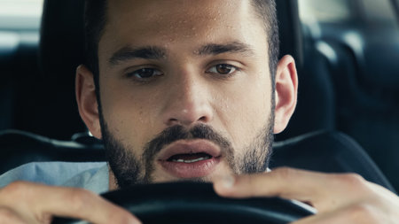 portrait of man with sweat on forehead driving car in hot summer dayの写真素材
