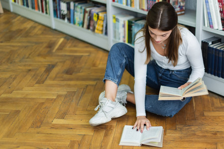 high angle view of teenage girl with books sitting on floor in library