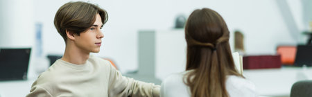 guy sitting in library reading room and looking at blurred teenage girl, bannerの写真素材