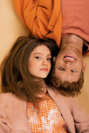 top view of happy and young redhead man lying together with pretty girlfriend on beige