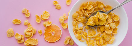 top view of dried oranges near bowl with corn flakes and organic milk on pink, banner