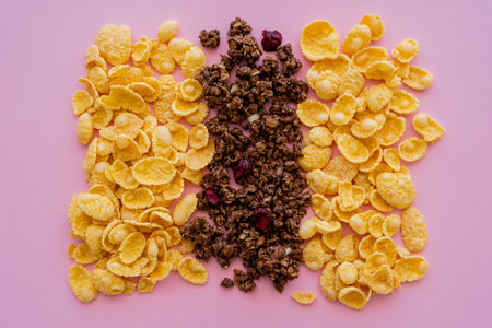 flat lay view of crispy corn flakes and tasty granola isolated on pinkの写真素材