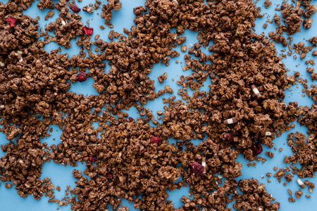 top view of crunchy granola with dry red berry on blue background