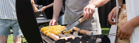 Cropped view of interracial friends cooking sausages and corn on grill in backyard, banner