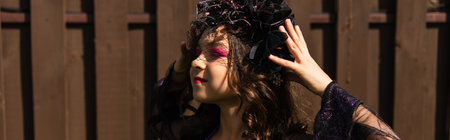 girl in witch costume adjusting black wreath outdoors, banner