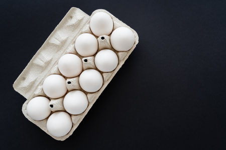 Top view of organic while chicken eggs in cardboard box isolated on blackの写真素材