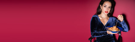 elegant brunette woman with delicious pasta looking at camera on red background, bannerの写真素材