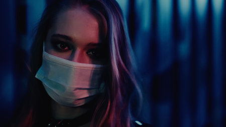 Young woman in protective mask looking at camera in nightclubの写真素材