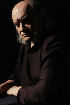 strict and thoughtful priest looking at camera isolated on black