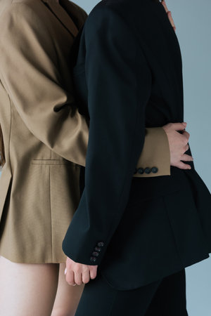 cropped view of lesbian woman hugging girlfriend in black blazer isolated on grey