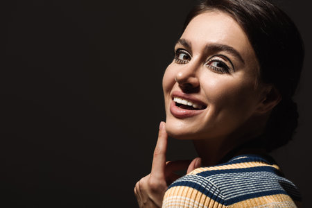 portrait of happy pin up woman in striped turtleneck looking at camera isolated on black