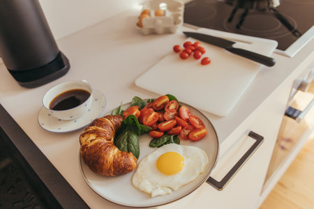 Delicious breakfast with egg and croissant near coffee in kitchenの写真素材