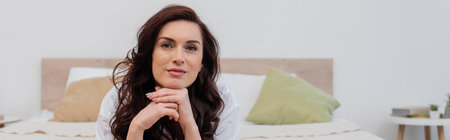 Woman in white shirt looking at camera while lying on bed, banner