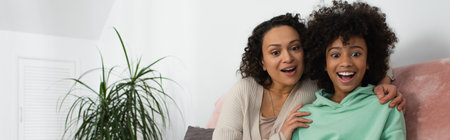 happy african american mother hugging excited preteen daughter, banner