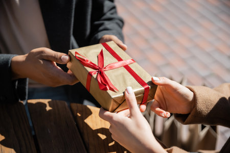 partial view of african american man giving new year present to woman outdoorsの写真素材