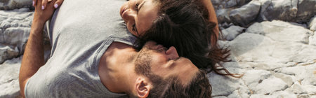 top view of bearded man and woman with closed eyes lying on rocks, banner