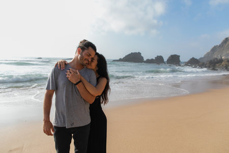 happy woman in dress hugging cheerful boyfriend near ocean in portugalの写真素材