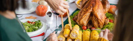 Cropped view of woman taking corn near grandchild and thanksgiving turkey at home, bannerの写真素材