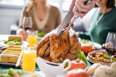 Cropped view of man cutting delicious turkey during thanksgiving dinner at homeの写真素材