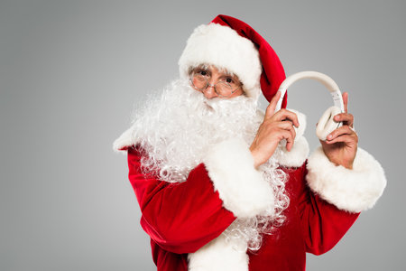 Santa claus in eyeglasses holding headphones isolated on greyの写真素材