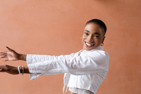 Smiling and stylish african american woman outstretching hands and looking at camera outdoorsの写真素材