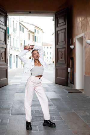 Smiling fashionable african american woman closing eyes on urban street in Trevisoの写真素材