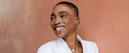Smiling short haired african american woman looking away near building on street, bannerの写真素材