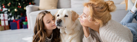 Smiling parent looking at daughter and labrador during new year at home, banner