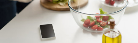 mobile phone with blank screen near bowl with vegetable salad and bottle of oil, bannerの写真素材