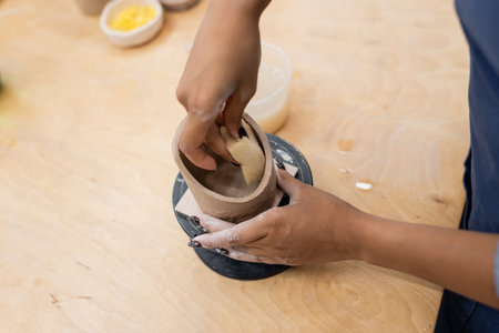 Cropped view of african american craftswoman forming clay product with spongeの写真素材