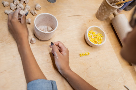 Cropped view of african american master holding clay sculpture near table in pottery workshopの写真素材
