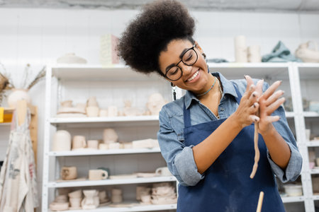 Cheerful african american craftswoman forming clay in pottery workshopの写真素材