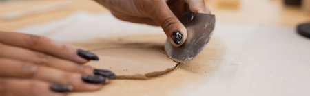 cropped view of african american woman with manicure holding stainless steel scraper while shaping clay piece, bannerの写真素材