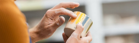 Cropped view of artisan checking ceramic cup in pottery studio, bannerの写真素材