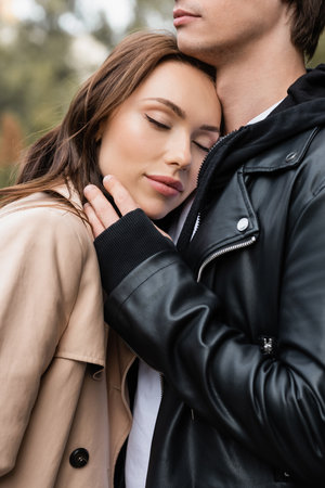 pretty young woman with closed eyes leaning on chest of boyfriendの写真素材